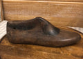 Wooden shoe on a wooden stand with a checkered tablecloth in the background